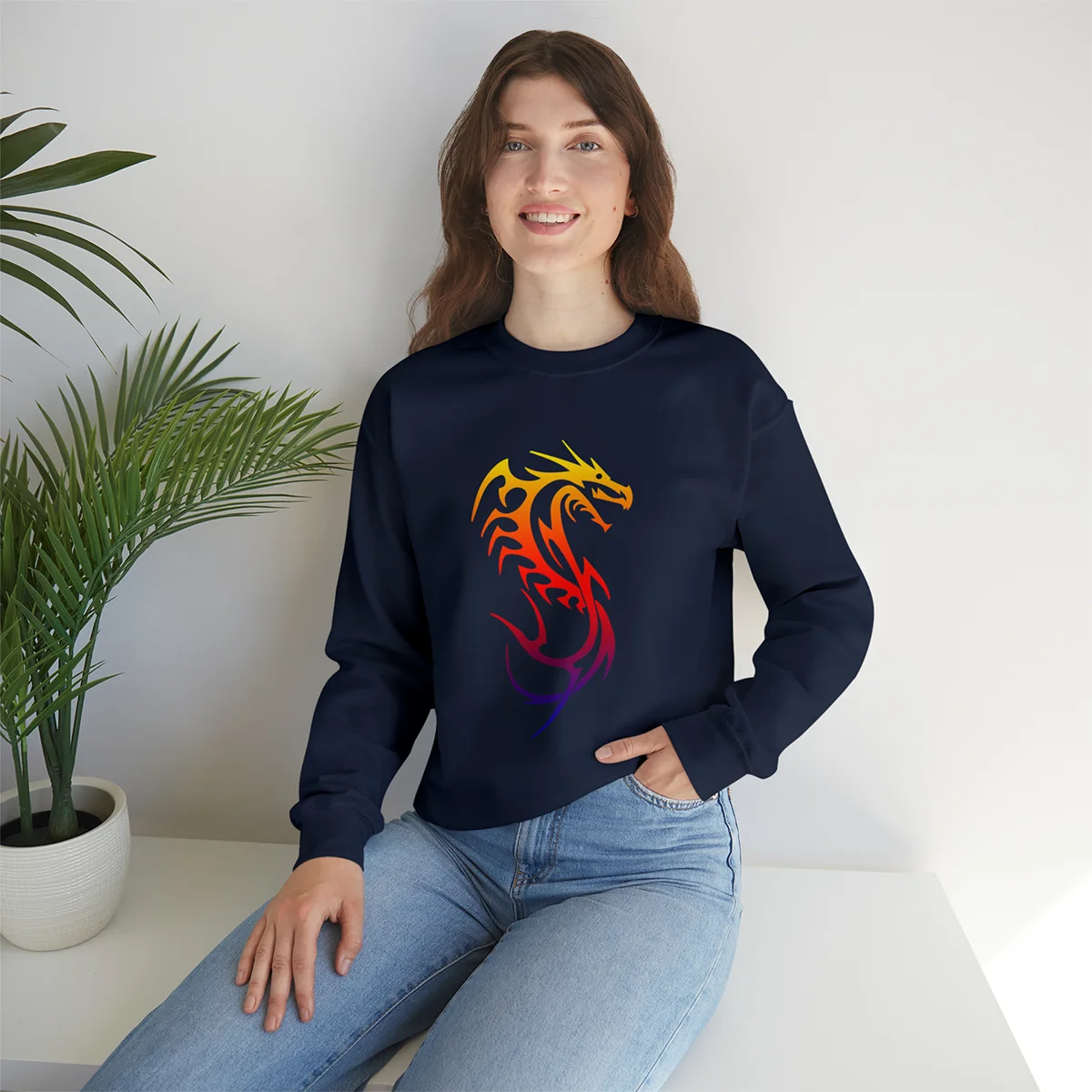 Woman wearing a navy sweatshirt with a colorful dragon design, sitting indoors.