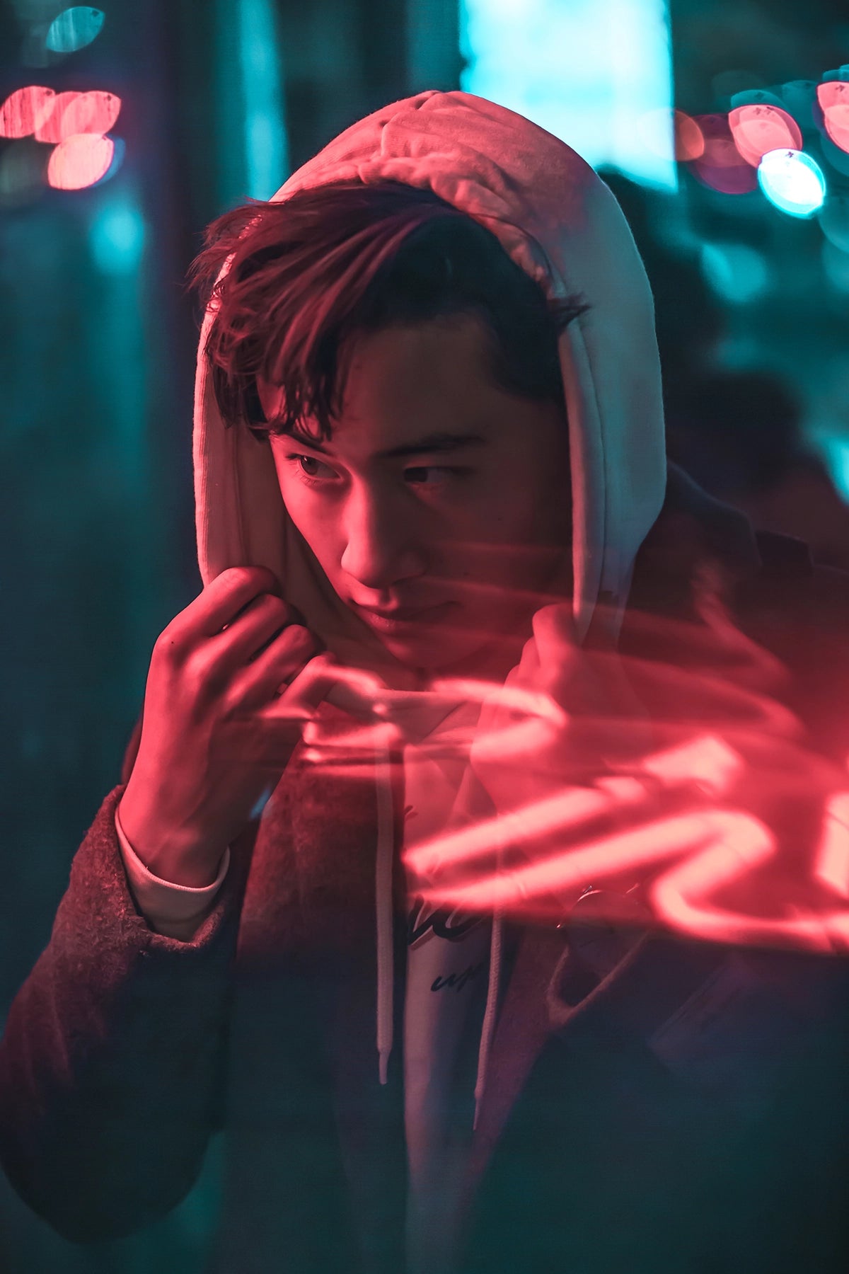 Person wearing a hooded jacket with neon lights in the background